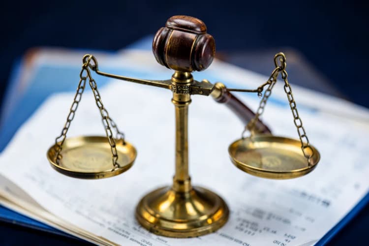 Balança da justiça com um martelo de juiz em cima de papéis